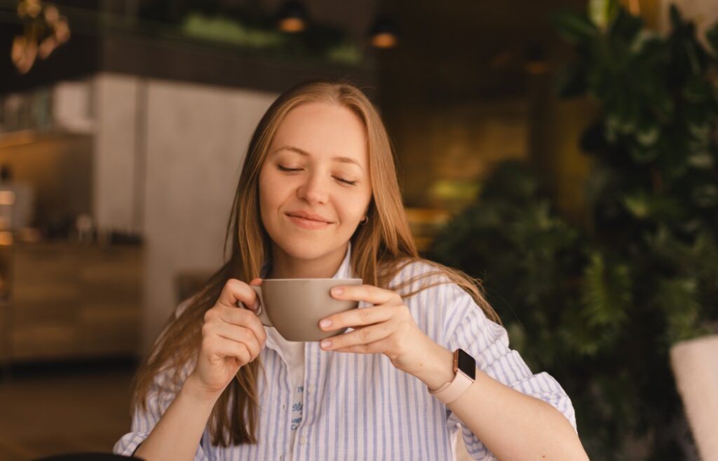 How to Maximize Your Dental Insurance Benefits After the 2026 Reset 12 Portrait of gorgeous blonde smiling lady smelling, enjoying of coffee and drinking cappuccino from cup while resting in restaurant. Woman wear stripped shirt.